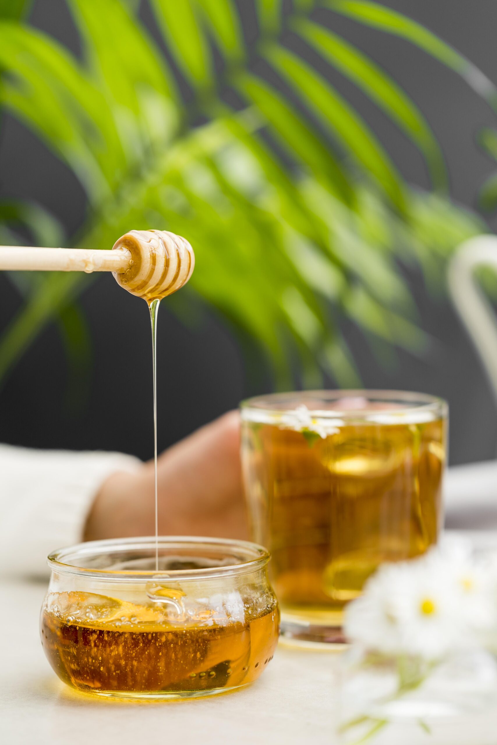 front-view-woman-holding-glass-with-tea-honey-dipper